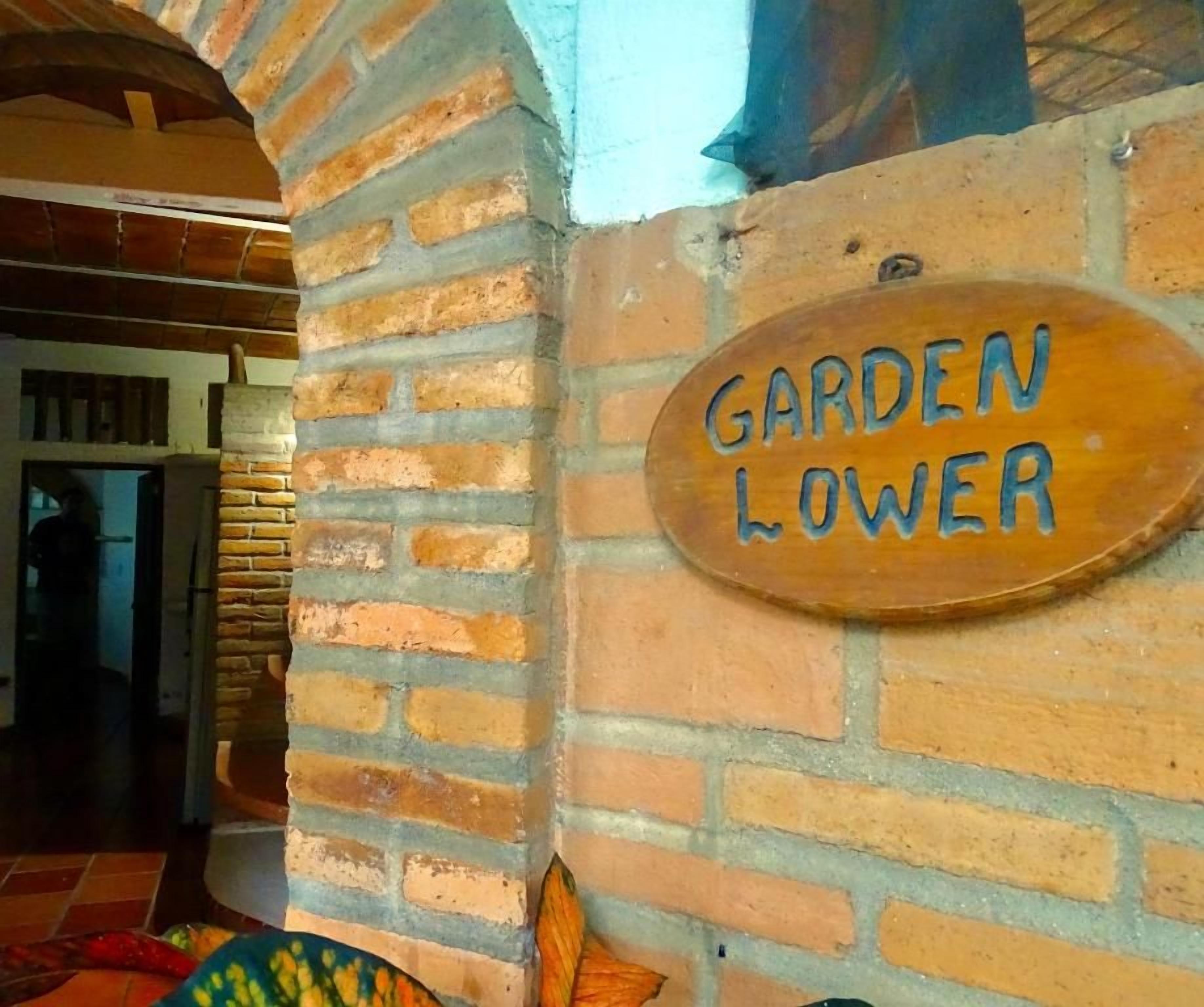 Un mur de briques sur lequel est fixée une pancarte en bois indiquant : « JARDIN INFÉRIEUR ».