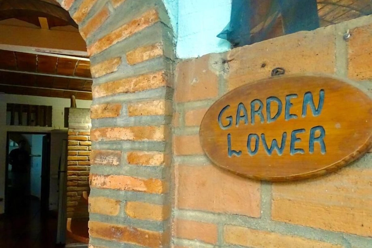 A brick wall with a wooden sign that reads "GARDEN LOWER".