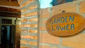 A brick wall with a wooden sign that reads "GARDEN LOWER". - Jardin De Playa Sayulita (Sayulita)