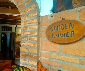 Eine Ziegelwand mit einem Holzschild, auf dem 'GARDEN LOWER' steht.