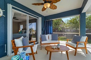 A balcony with a ceiling fan, wooden chairs with striped cushions, a round table, and a view of the outdoors. - Sunny Cape Coral 4BR Heated Pool & Screened Lanai (Cape Coral)