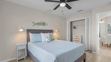 A bedroom with a bed, nightstands, a ceiling fan, and a fish wall decoration.