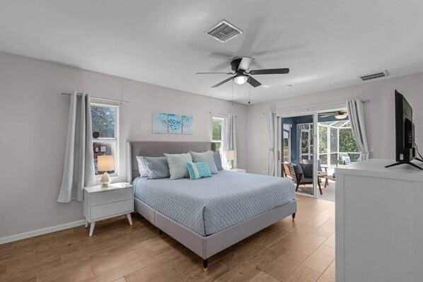 A bedroom with a bed, a ceiling fan, a window, and a television. - Sunny Cape Coral 4BR Heated Pool & Screened Lanai (Cape Coral)