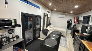 Una habitación de hotel compacta con kitchenette, una cama, televisión y un pequeño comedor.