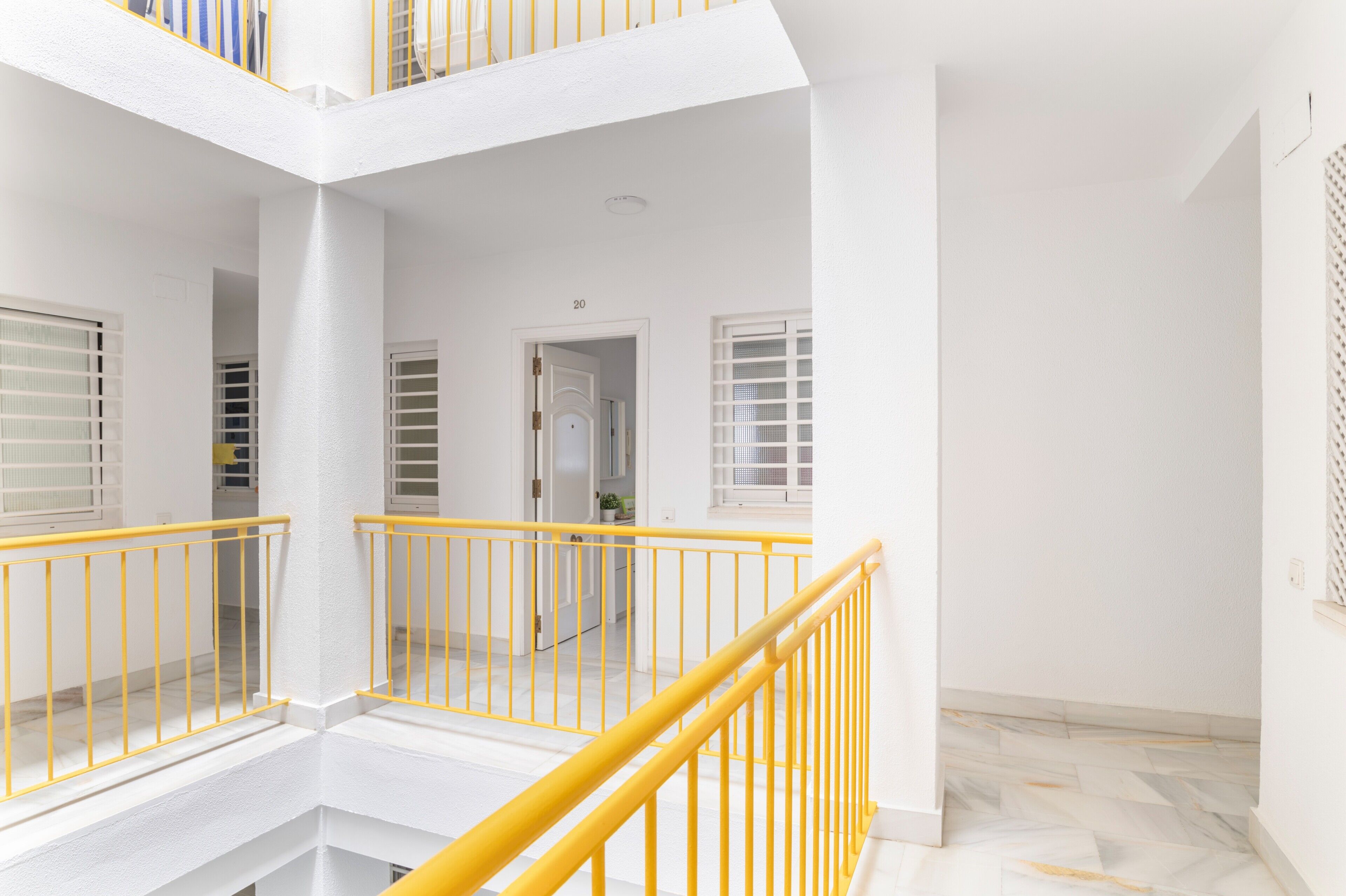 A white interior with yellow railings, a door with a number, and a patterned floor.