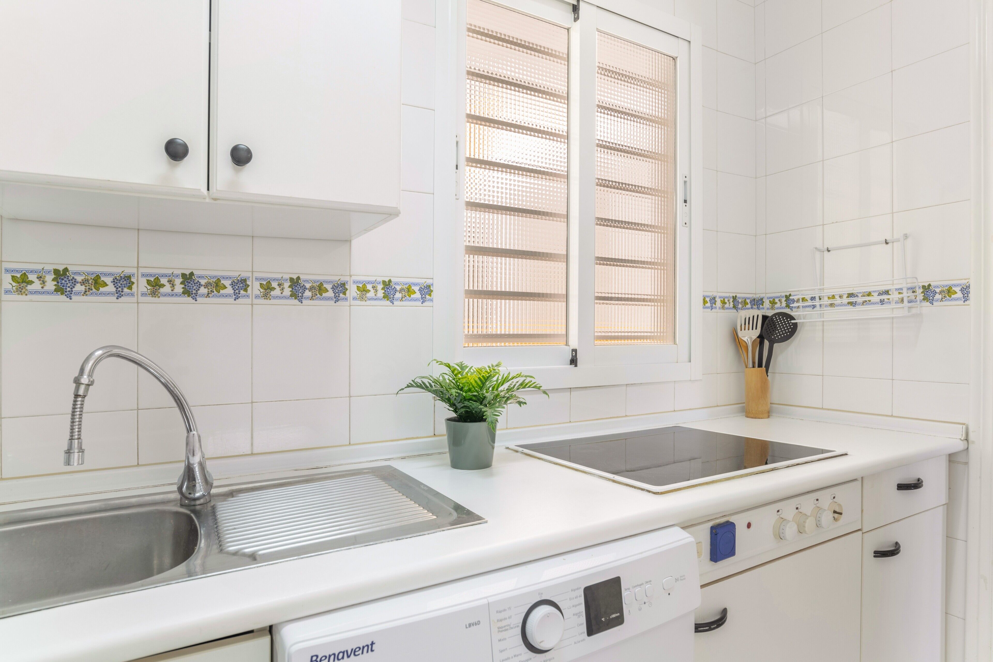A kitchen with a sink, stove, and a window with blinds.