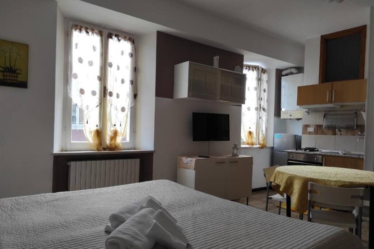 A hotel room with a bed, a desk, a television, and a kitchenette.