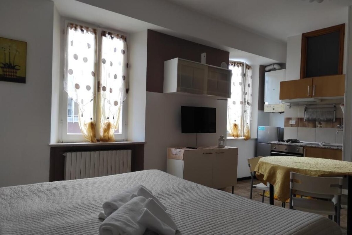 A hotel room with a bed, a desk, a television, and a kitchenette.