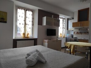 A hotel room with a bed, a desk, a television, and a kitchenette. - Monolocali Da Vinci (Falconara Marittima)