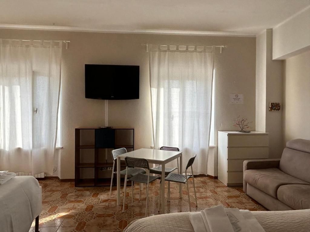 Una camera d'albergo con un letto, un divano, un tavolo da pranzo con sedie, una TV fissata al muro e un piccolo mobile.
