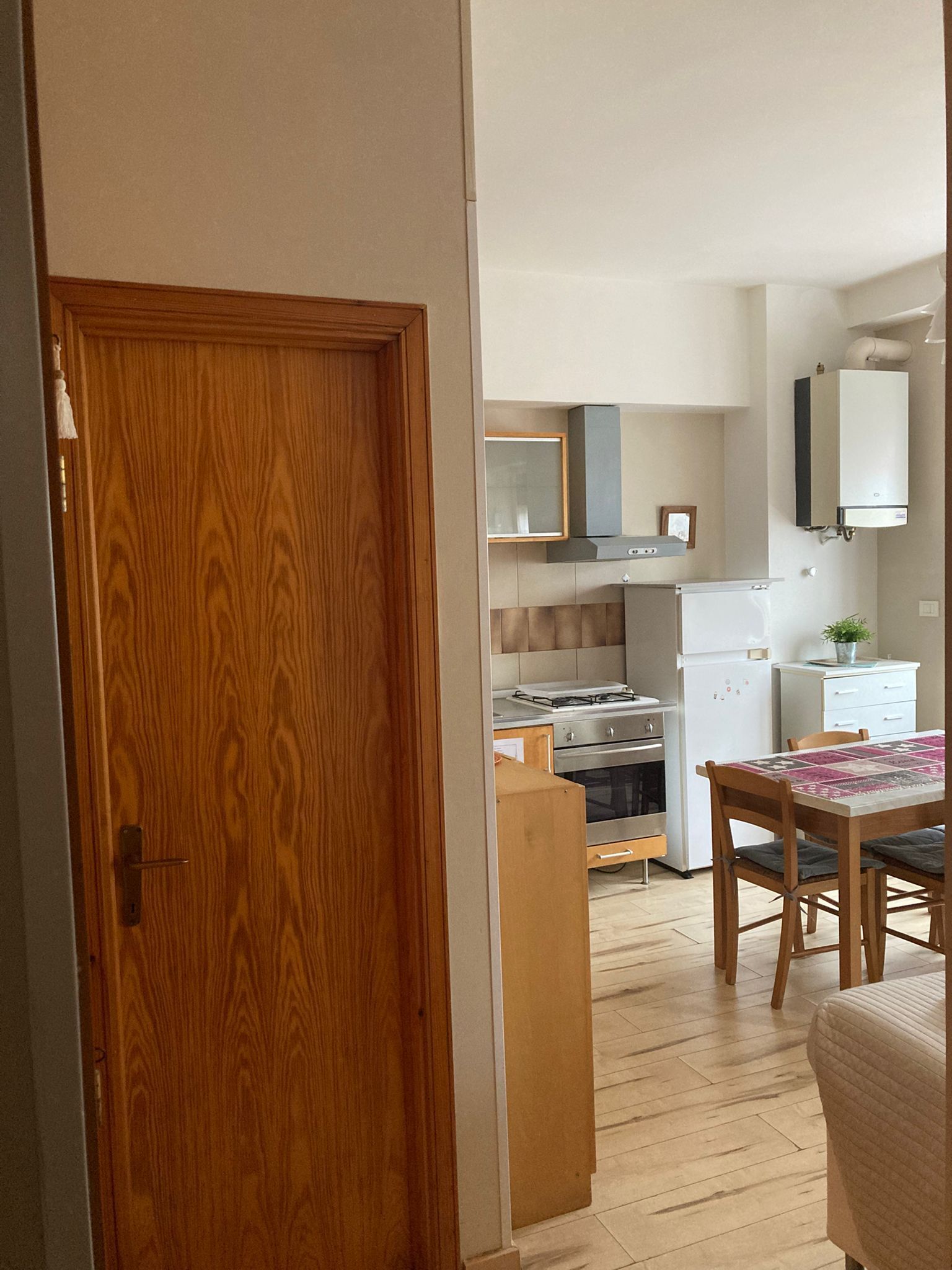 Una cucina con mobili in legno, un fornello, un frigorifero e un tavolo da pranzo con sedie.