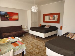 A bedroom with a bed, a sofa, a small table with a bowl and remote, and a mirror on the wall. - Monolocali Da Vinci (Falconara Marittima)