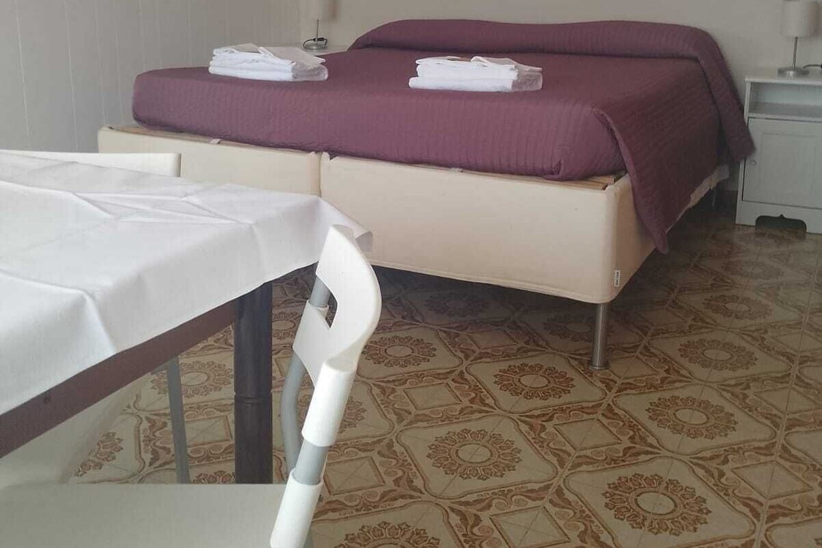 A hotel room with a bed, a table, and a chair.