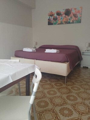A hotel room with a bed, a table, and a chair.