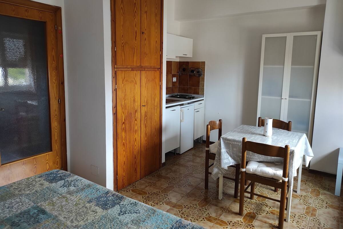 A compact kitchen with a dining area, wooden cabinets, and a tiled floor.