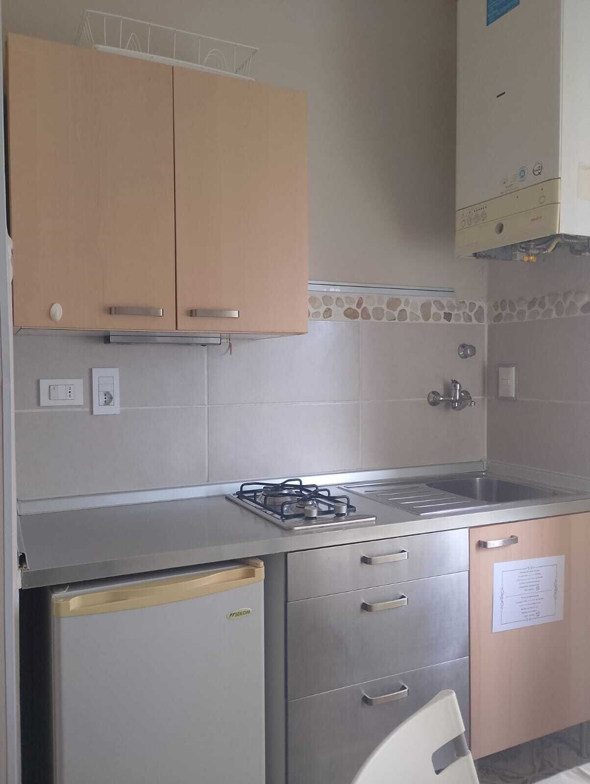Una cucina compatta con piano cottura a gas, lavello e pensili.