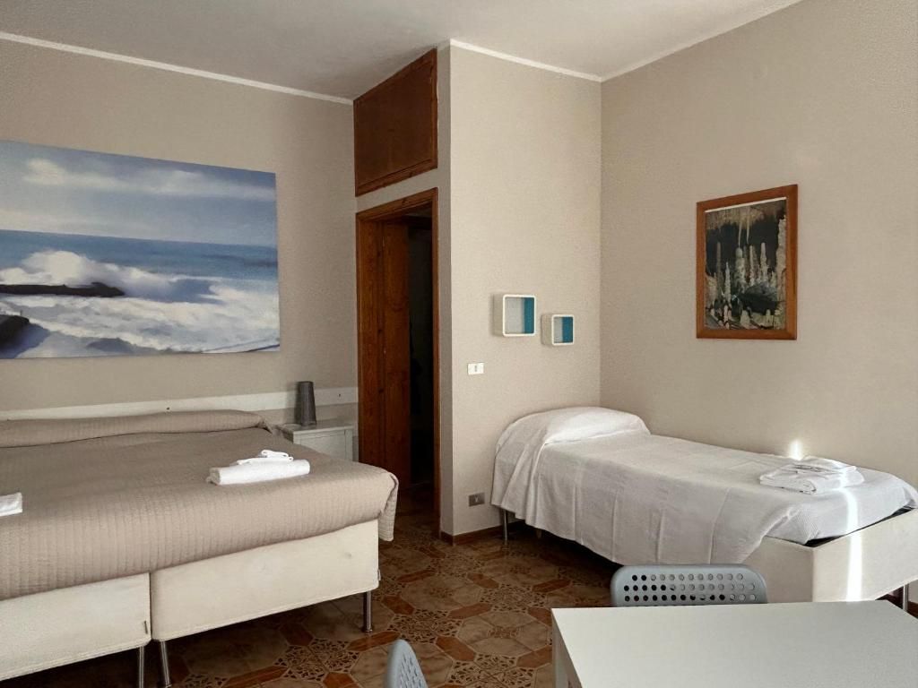 Habitación de hotel con dos camas, un cuadro de una playa, una mesita y una silla.