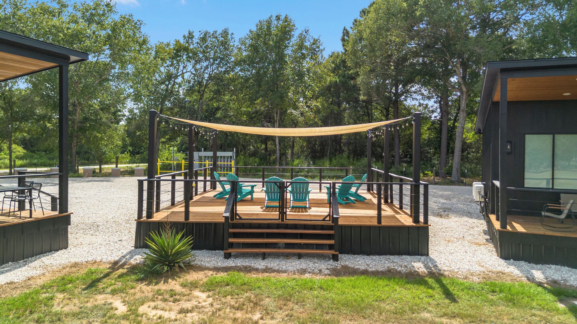 A deck with outdoor seating and a canopy, surrounded by trees.