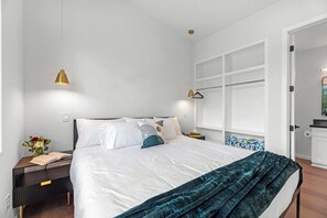 A modern bedroom with a large bed, bedside tables, a wardrobe, and a window.
