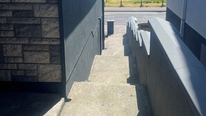 A concrete staircase leading to a balcony overlooking a body of water and a distant shoreline.