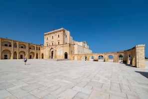 Un patio amplio con un edificio grande que tiene varios arcos y una entrada principal.