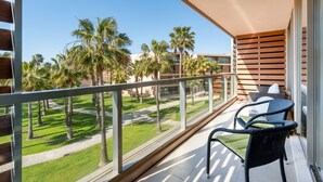 A balcony with a view of a landscaped area with palm trees and a pathway.