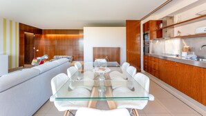 A modern kitchen with a glass dining table, wooden cabinets, and a built-in oven.