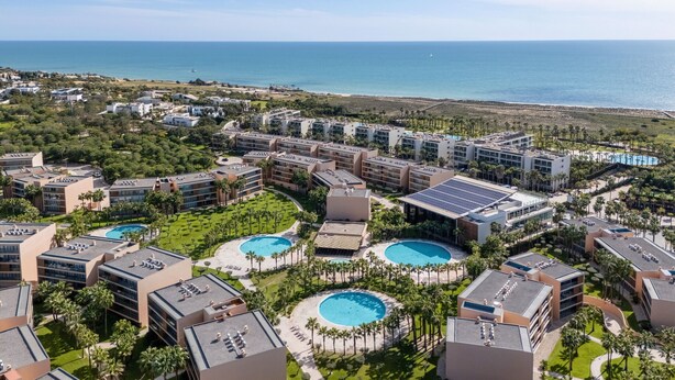 A resort with multiple buildings, swimming pools, and a view of the ocean.