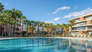 A swimming pool surrounded by palm trees and modern buildings.