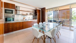 A modern kitchen with built-in appliances, a glass dining table, and a sliding glass door to a balcony.