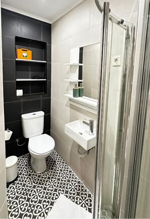 Une salle de bain avec des toilettes, un lavabo et une douche.