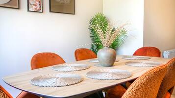 Una mesa de comedor con individuales tejidos, rodeada de sillas tapizadas en color naranja.