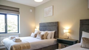 Une chambre d’hôtel avec deux lits, une grande fenêtre et une table de chevet avec une lampe.