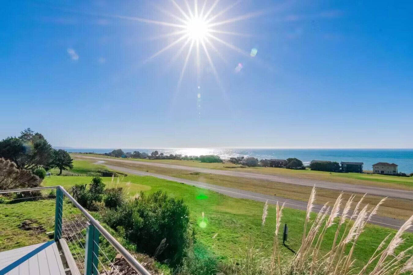 A coastal road with a clear view of the ocean and a distant shoreline.