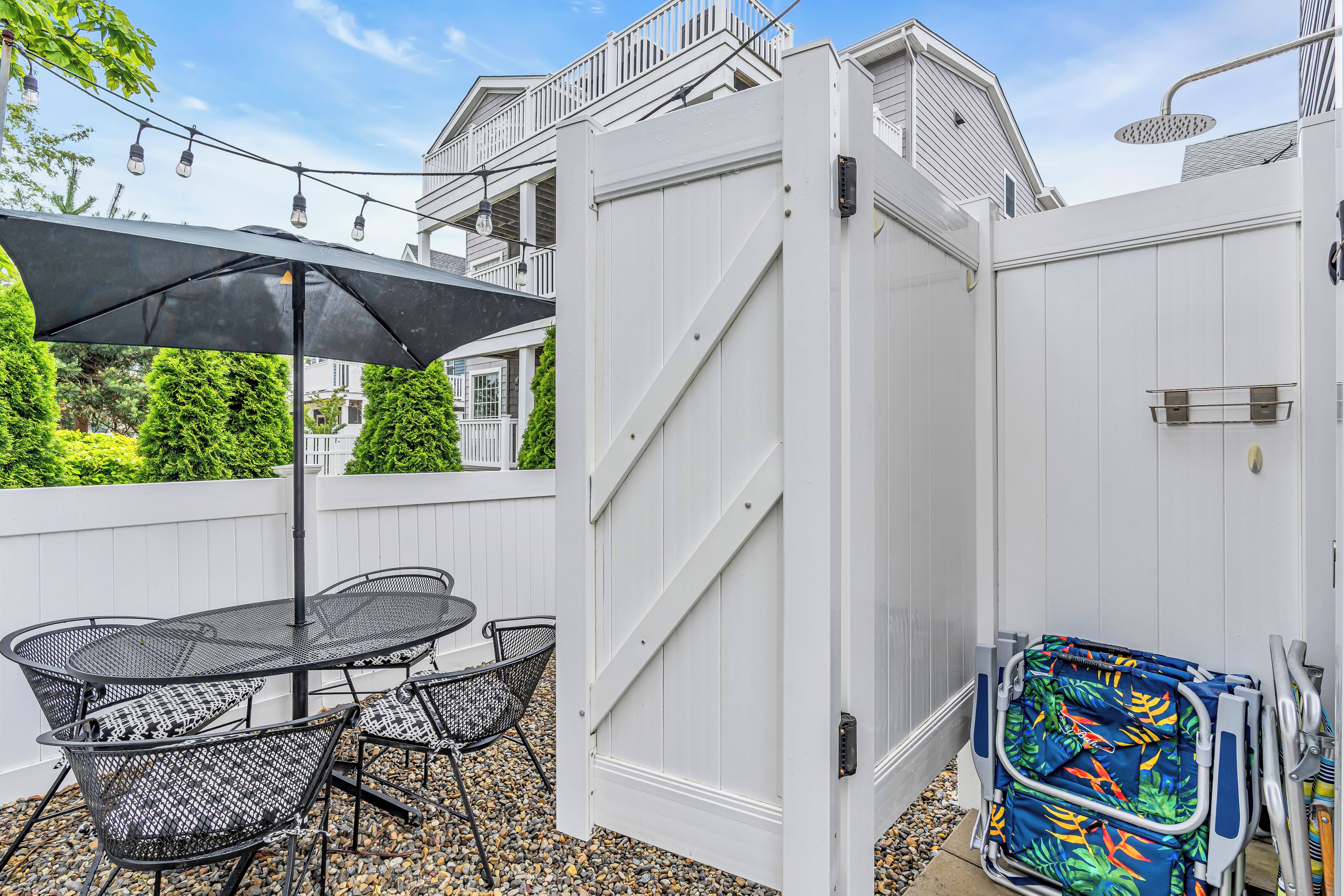 A patio with a round table and chairs, a white gate, and a colorful beach bag.