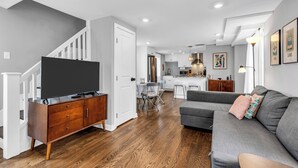Un salon moderne avec un canapé gris, un meuble de rangement en bois et un escalier.