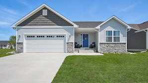 A single-story house with a garage, a front porch, and a stone foundation.