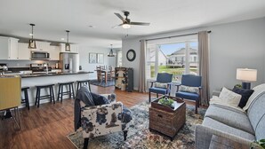 A modern kitchen with a central island, bar stools, and a dining area with a view.