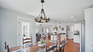 A dining area with a wooden table, chairs, and a chandelier.