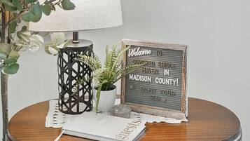 A round wooden table with a lamp, a welcome sign, and a small potted plant.