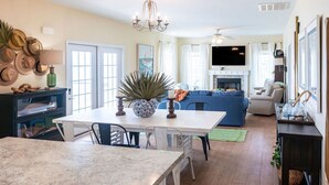 A spacious living area with a fireplace, a dining table, and a kitchen area with a large island. - Welcome to Core Sound Retreat – Your Peaceful Down East Getaway (Davis)