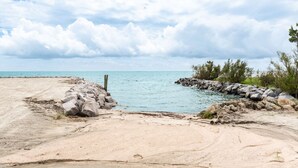 A sandy beach with a rocky breakwater and calm sea under a partly cloudy sky. - Welcome to Core Sound Retreat – Your Peaceful Down East Getaway (Davis)