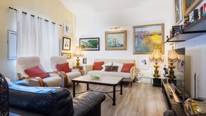Un salon comprenant un canapé, des fauteuils, une table basse et des œuvres d’art accrochées aux murs.