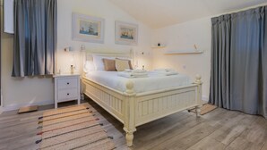 Une chambre à coucher avec un lit, des tables de chevet, un tapis et des rideaux.