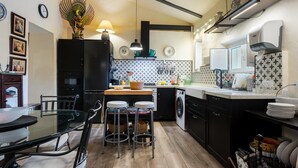 Une cuisine compacte comprenant un coin repas, un lave-linge et un évier.