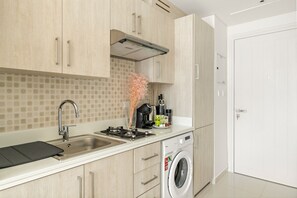 A modern kitchen with a stainless steel sink, a built-in stove, and a washing machine. - Modern Studio with Beach Access, Palm Jumeirah (Dubai)