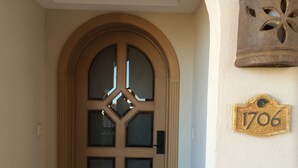 A wooden arched door with glass panels and a number plaque reading "1706" on the wall beside it.