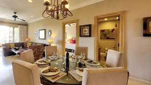 A dining area with a round glass table set for four, surrounded by beige upholstered chairs.