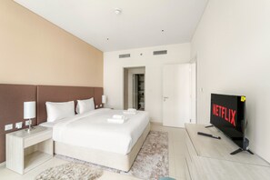 Een moderne hotelkamer met een groot bed, een flatscreen-televisie, een nachtkastje met een lamp en een deur naar een kast.