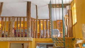 Ein Zimmer mit einer Holztreppe, einem Ventilator und einem Bett mit einer Streifenoptik.